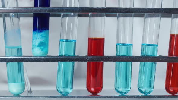 Putting a Flask with Blue Solution in Stand with Other Mixtures Closeup