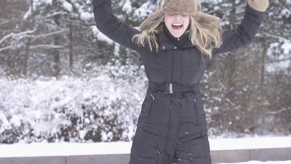 Happy Young Woman Playing in Snow in Winter Holidays