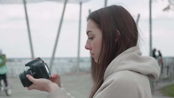 Young Woman Holding Photo Camera and Focus on an Object is Smiling and Taking a Photo in the Park