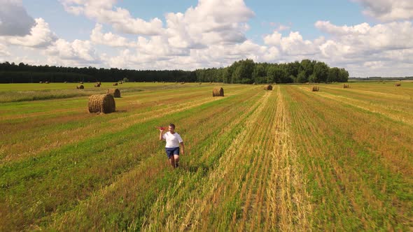 A Boy Runs in a Field with a Plane in His Hand Against a Beautiful Sky