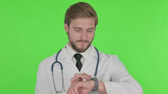 Young Doctor Using Smartwatch on Green Background