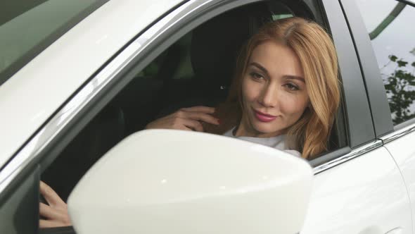 Stunning Red Haired Woman Looking at the Side Mirror Sitting in Her Car