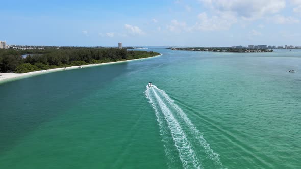 Camera catches up to a boat driving along the beach in coastal Florida. The boat is moving at full t