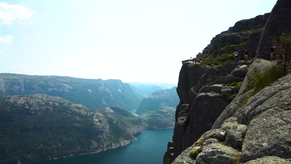Side view of Preikestolen with tourists walking on the path in Norway.