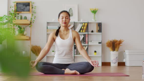 Calm of Attractive Asian woman practice yoga lotus pose to meditation in bedroom