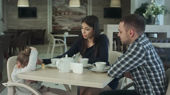 Ordinary Family of Three with Little Daughter in Cafe Father and Mother Reassuring Their Child