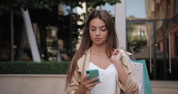 Front View of Joyful Brunnette Woman Looking at Phone Screen While Scrolling News Feed. Millennial