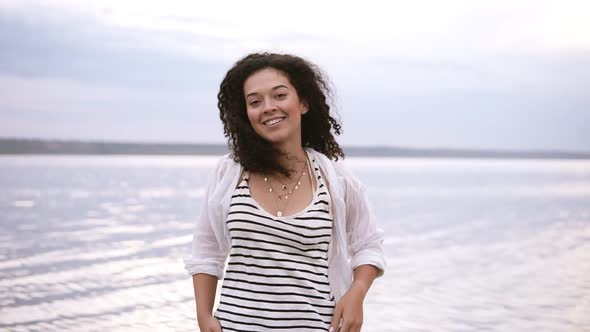 Portrait of a Beautiful Curly Brunette Standing and Posing for Camera