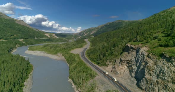 Ariel View of Cars Driving the Mountain Road and the River Going Over the Horizon in Parallel Way