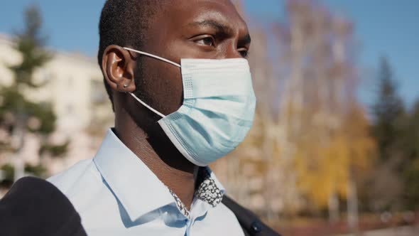 Portrait of African American Business Man in Mask, Smartphone in Hands. City Walk Down the Street