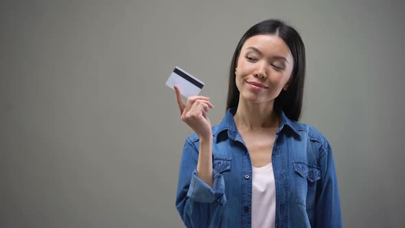 Smiling Asian Woman Holding Credit Card and Thinking About Shopping, No Limits