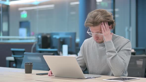 Young Businessman with Laptop Having Headache
