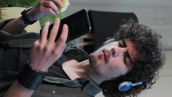 Young Man Listening to the Music and Gesturing While Eatting an Apple Vertical Video