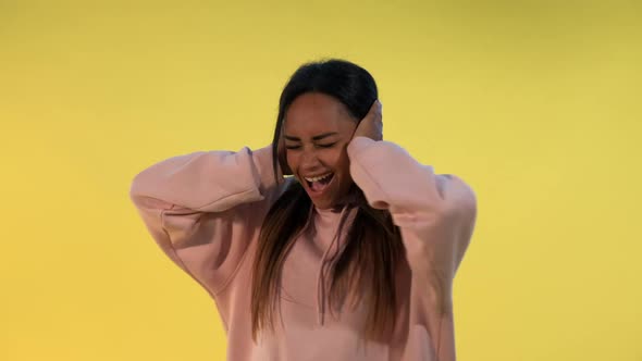 Desperate African Woman Screaming and Covering Ears on Yellow Background