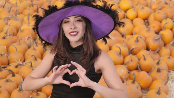 Beautiful girl in a black dress and a purple witch hat poses against the backdrop of a large number