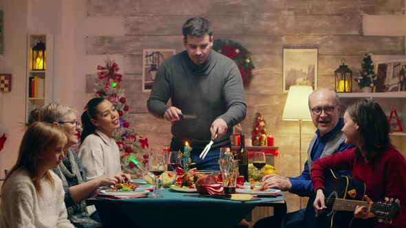 Girl Singing a Song on Guitar While Her Father Is Slicing the Chicken