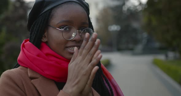 Young Black Girl in a Coat and Scarf Warms Her Hands
