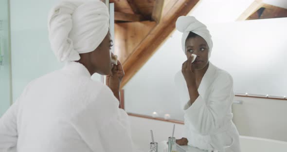 African american attractive woman removing make up in bathroom