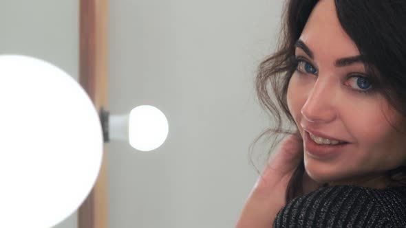 Close-up. Attractive Young Girl Posing Looking at the Camera in a Beauty Salon in Front of a Mirror