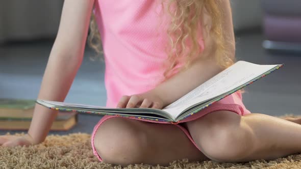 Female Child Sitting on Carpet and Reading Fairy Tales