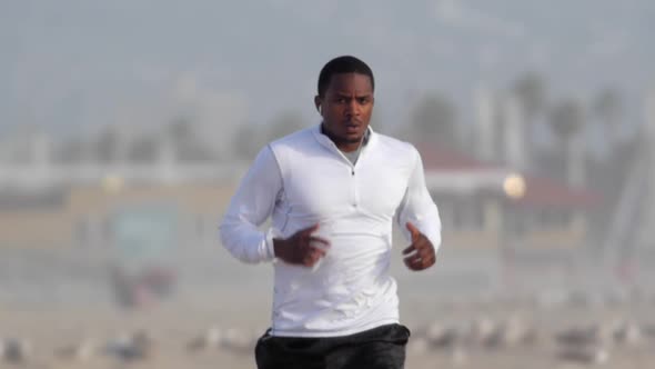 A young man runner  getting a workout running in the sand on the beach.