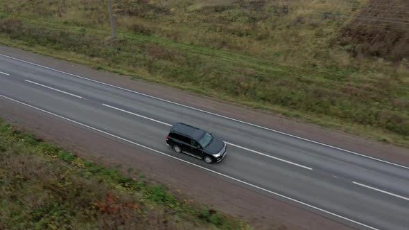 Aerial View of Black Car Moves on Road with Beautiful Landscape Between Fields. Top View. Shooting