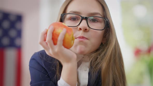 Closeup Happy Confident Girl in Eyeglasses Chewing Delicious Vitamin Apple Looking at Camera