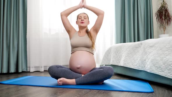 Beautiful Smiling Pregnant Woman Breathing and Meditating at Big Window on Sunny Morning