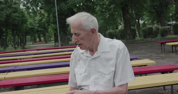 View of Granddad Smoking Cigarette on Park Bench