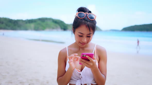 Portrait of Happy Smiling Woman Using a Mobile Phone on the Beach Posting a Picture Online