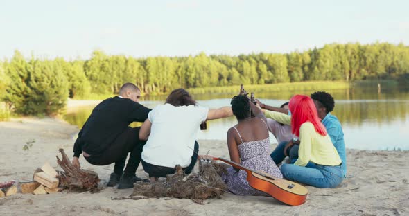 Team of Friends is Sitting By Lake on Sand Beach the Last Days of Vacation They Spend Time Together