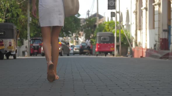 Woman Legs Walk Along Asphalt Road Against Local Vehicles