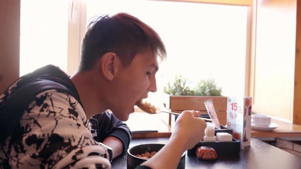 Young Man Eating Delicious Soup in a City Cafe