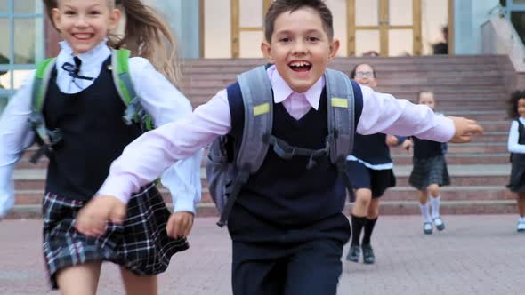 Schoolboy in Uniform and Friends Run Along School Yard