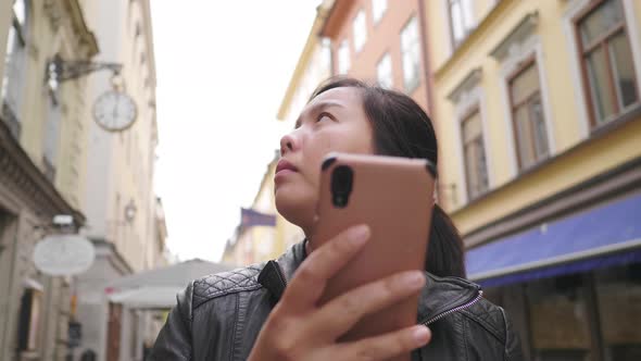 Asian woman using smartphone and looking around in town