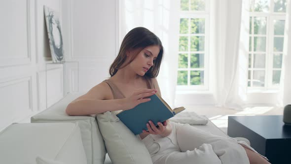 Romantic Woman Reading a Book at Home on the Couch