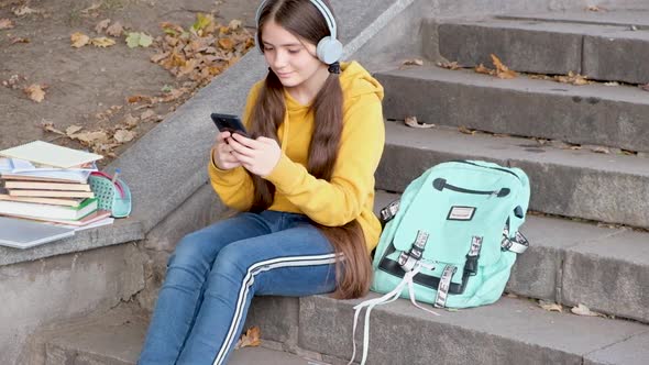 A Teenager Types Text or Plays on a Smartphone and Laughs