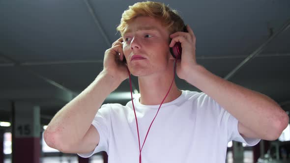 Redhead Man In Headphones Listening Music At Parking