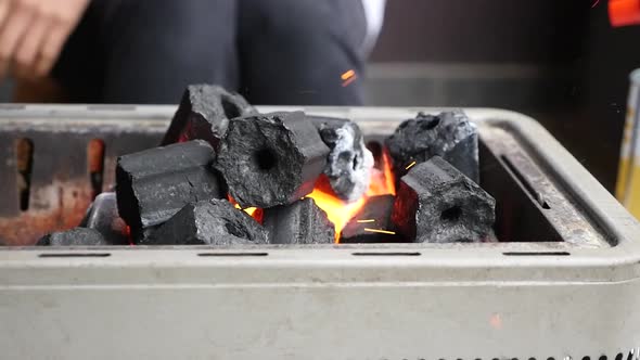 Handheld slow motion of charcoal being lit on fire with sparks flying