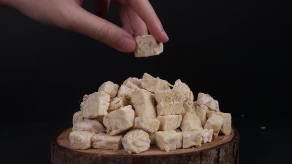 Placing One Raw Cubes Of Tempeh On A Pile Of Raw Tempeh