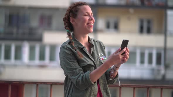 Pretty red-haired girl with braids using mobile phone.