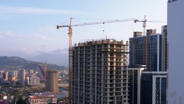 Building Construction. A Crane on a Construction Site Lifts a Load. Workers at a Construction Site