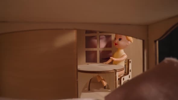 Smiling Little Child Peeks Into Window at Small Doll in Room