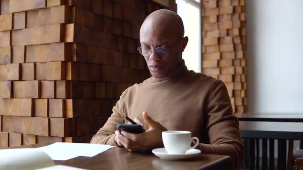 Young African American Business Man with Freckles on His Face Typing on a Smartphone