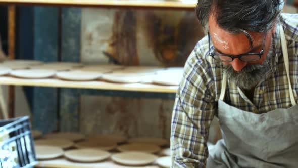 Male potter scrapping out the extra clay from the ceramic bowl 4k