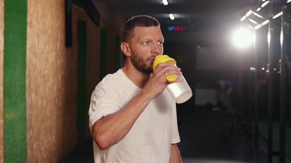 Lifestyle Portrait of Muscular Man Drinking Water in the Gym