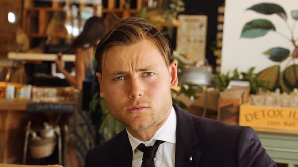 Businessman Looking To Camera Then Away In Cafe