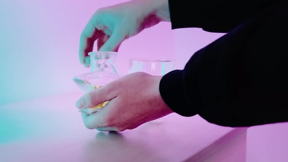 Closeup of a Man Pouring Vitamins Into His Hands and Drinking Water
