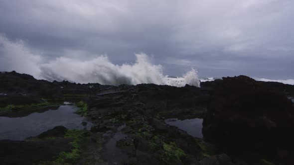 Panning view of waves shooting up on rocky beach