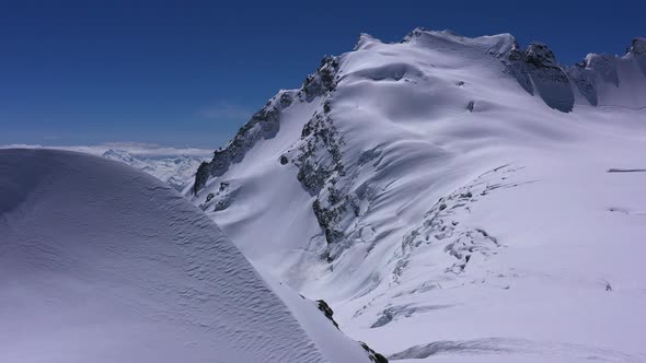 Aerial view of snow mountain range landscape in Georgia Jantugani Pass under blue sky.